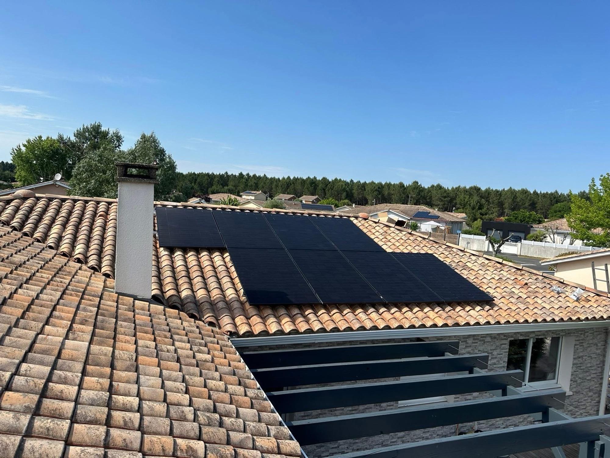 Panneaux photovoltaïques noirs posés sur une toiture en tuiles d'une maison