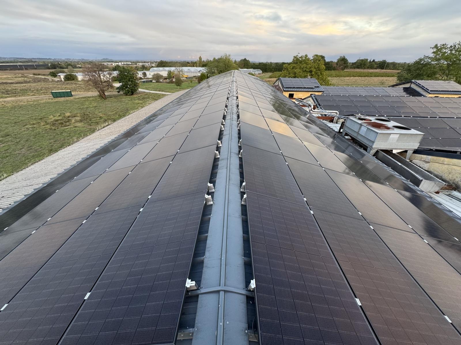 Longue toiture de bâtiment professionnel couverte de panneaux photovoltaïques, vue depuis le faîtage