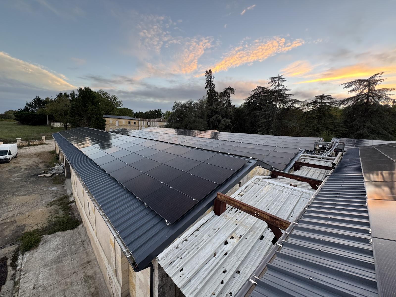 Bâtiments aux toitures équipées de panneaux photovoltaïques sous un ciel de fin de journée